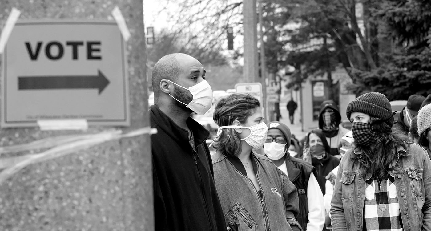 Voters wearing masks stand in line at the polls.